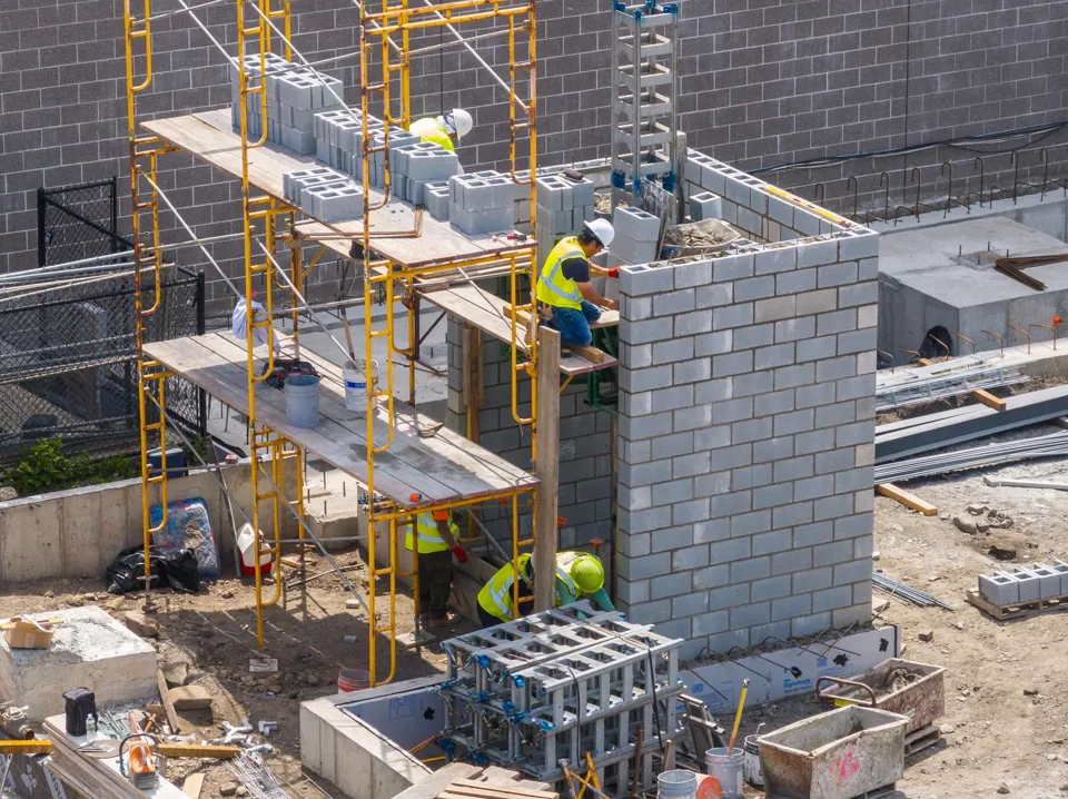 Crew on scaffolding laying CMU block for a building's elevator core