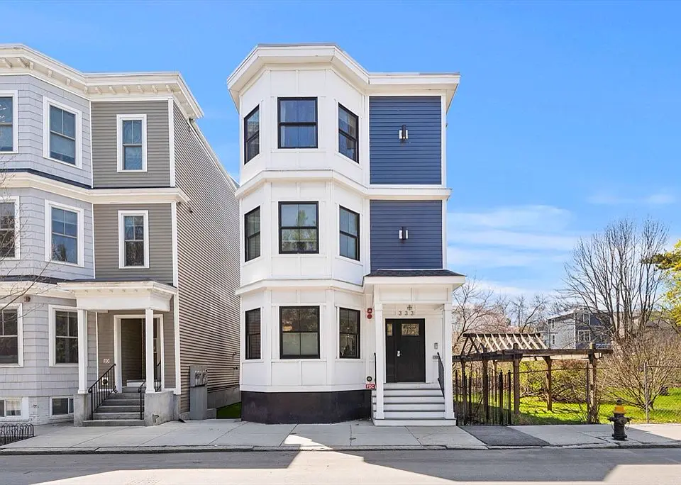 Pair of renovated three-family homes with white bays, navy and gray siding and new front steps
